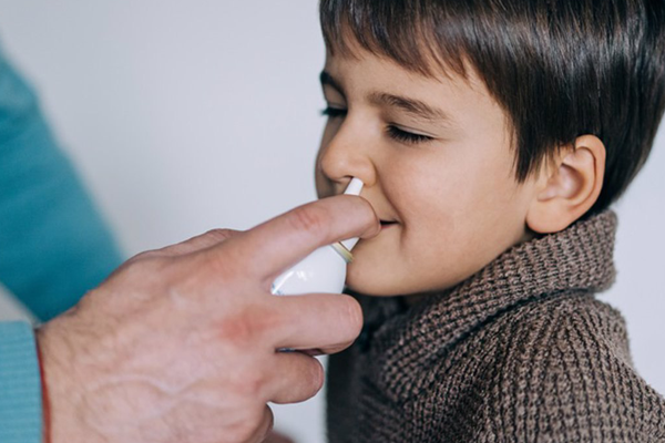 niño recibiendo un chisguete de líquido nasal por un otorrino